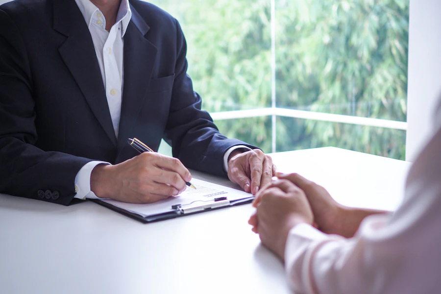 A man interviewing a woman while writing on a paper notes to fill a position after agent turnover