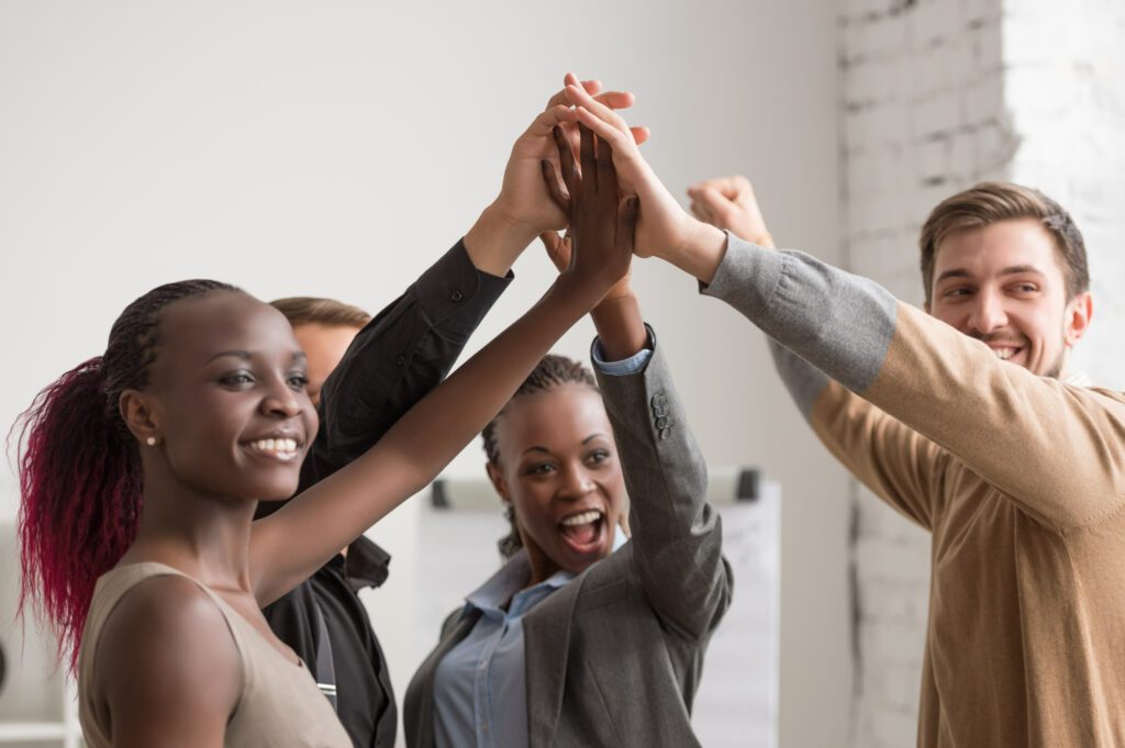 Employees high-fiving each other and in a diverse workplace