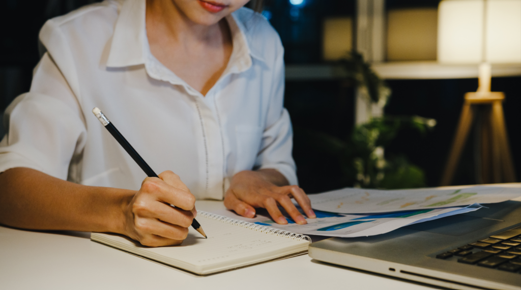 Woman writing on a notebook on a desk at work