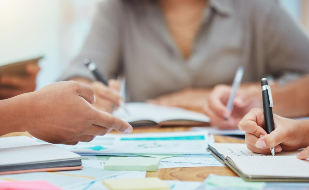 A close up of hands writing notes with a pen on a notebook on customer success in digital transformation