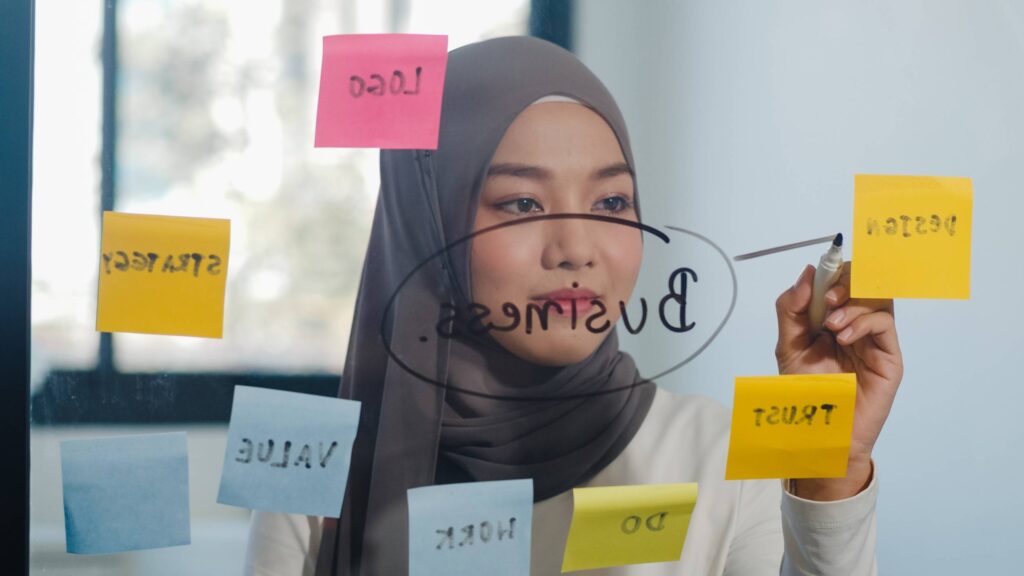 Woman in tech writes on glass board for work-related topics