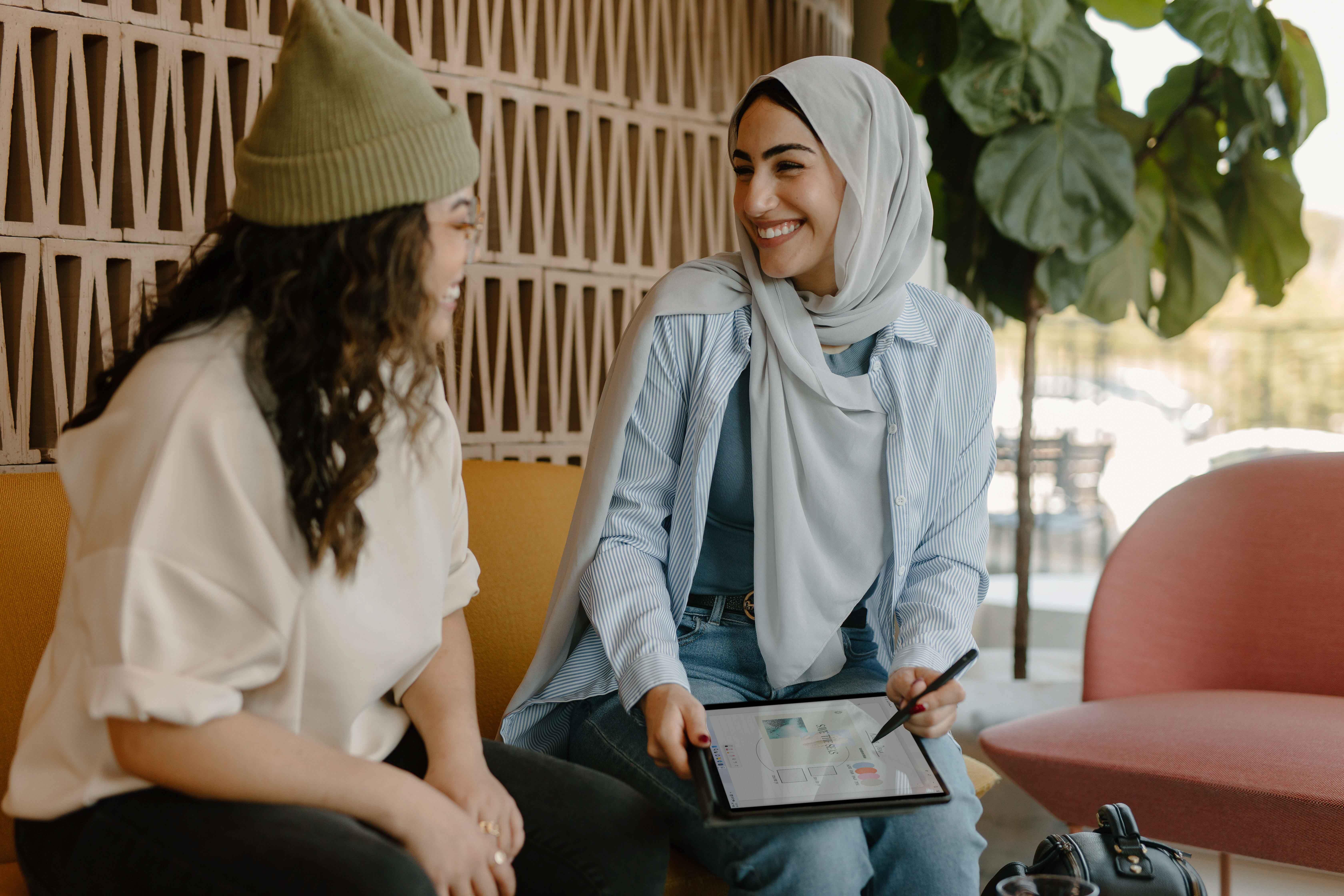 Two females sitting in a coffee shop using an iPad and being self-sufficient through Intelligent Process Automation