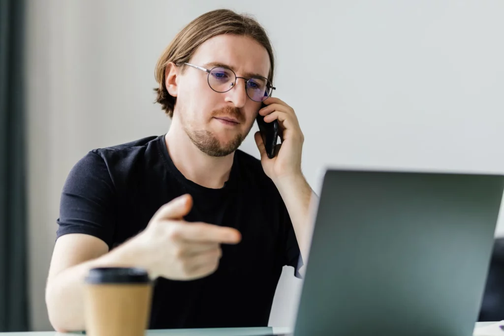 A customer looking at his laptop screen while talking on the phone to a customer service agent, which is an example of an omnichannel experience
